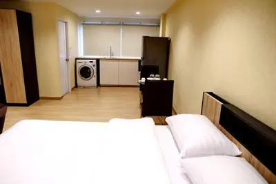a room with a bed and a kitchen with a washing machine at The Kaze 34 Hotel and Serviced Residence in Bangkok