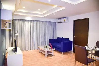 a living room with a blue couch and a table at The Kaze 34 Hotel and Serviced Residence in Bangkok