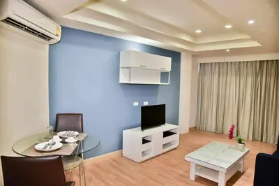 a living room with a glass table and a tv at The Kaze 34 Hotel and Serviced Residence in Bangkok