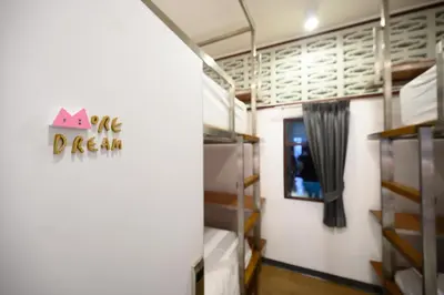 a room with bunk beds and a sign that reads the dream at REST IS MORE hostel in Bangkok