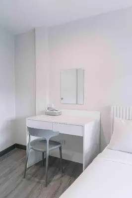 a white desk with a chair next to a bed at Ma Non Nont Hotel & Apartment in Nonthaburi