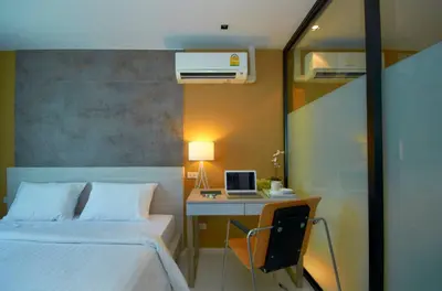 a bedroom with a bed and a desk with a computer at The Present Sathorn in Bangkok