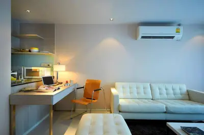a living room with a couch and a desk with a computer at The Present Sathorn in Bangkok
