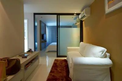 a living room with a white couch and a bedroom at The Present Sathorn in Bangkok