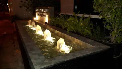 a water fountain with swans in a garden at night at Siam Bright Suite in Bangkok