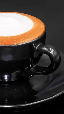a black cup of coffee sitting on a table at Siam Bright Suite in Bangkok