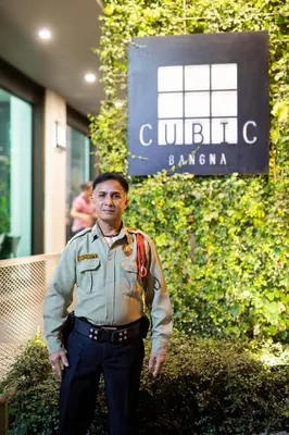 a man in uniform standing in front of a building at Cubic Bangna in Bangkok