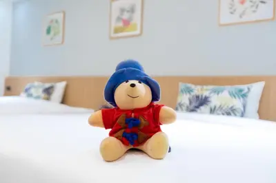 a stuffed teddy bear sitting on a bed at Cubic Bangna in Bangkok
