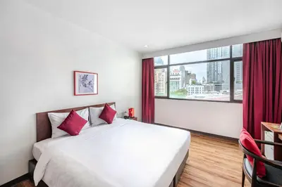 a bedroom with a large bed and a large window at Ruamchitt Plaza Hotel in Bangkok