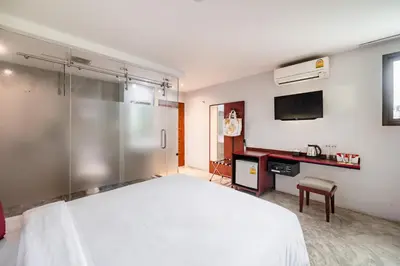 a bedroom with a large white bed and a desk at Ruamchitt Plaza Hotel in Bangkok