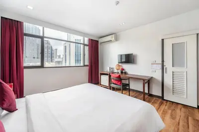 a bedroom with a bed and a desk and a window at Ruamchitt Plaza Hotel in Bangkok