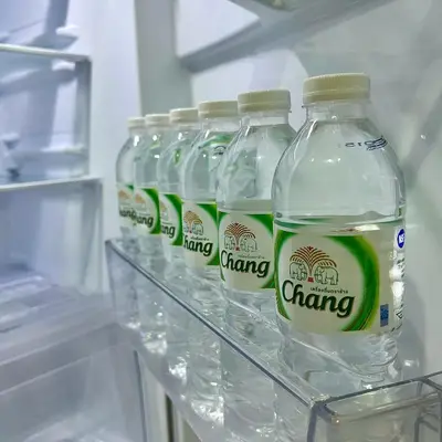 a row of bottles of water on a shelf in a refrigerator at The Gallery condominium in Samut Prakan