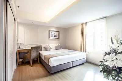 a bedroom with a bed and a desk and a window at Hope Land Hotel Sukhumvit 24 in Bangkok