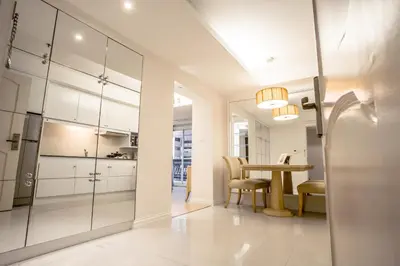 a kitchen and dining room with white cabinets and a table at Hope Land Hotel Sukhumvit 24 in Bangkok