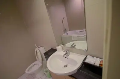 a bathroom with a sink and a toilet and a mirror at Hope Land Hotel Sukhumvit 24 in Bangkok