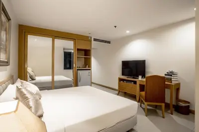 a bedroom with a bed and a desk and a television at Hope Land Hotel Sukhumvit 24 in Bangkok