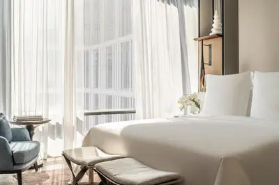 a bedroom with a bed and a chair and a large window at Four Seasons Hotel Bangkok at Chao Phraya River in Bangkok