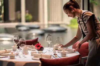 a woman standing at a table with wine glasses at Four Seasons Hotel Bangkok at Chao Phraya River in Bangkok