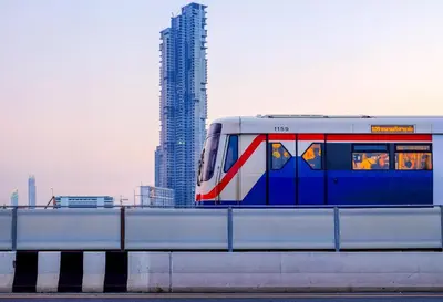 a train on a track in front of a tall building at Eleven Hotel Bangkok Sukhumvit 11 in Bangkok