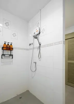 a shower in a white tiled bathroom at Bai Bua House Chatuchak in Ban Zong Katiam