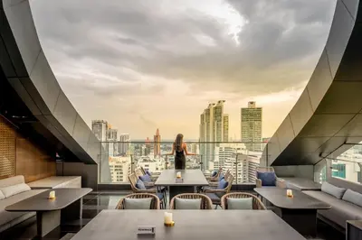 a woman standing in a restaurant with a view of the city at Carlton Hotel Bangkok Sukhumvit in Bangkok