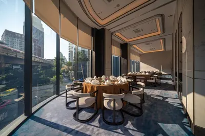 a dining room with tables and chairs and large windows at Carlton Hotel Bangkok Sukhumvit in Bangkok