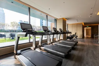 a row of treadmills in a gym with a large window at Carlton Hotel Bangkok Sukhumvit in Bangkok