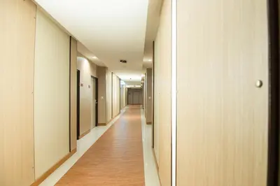 a corridor of an office building with wood floors and ceilings at Marsi Hotel Bangkok in Bangkok