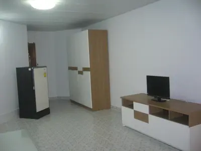 a room with a refrigerator and a table with a television at Poppular Palace Don Mueang Bangkok in Bangkok
