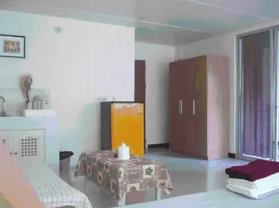 a room with a bed and a dresser and a table at Poppular Palace Don Mueang Bangkok in Bangkok