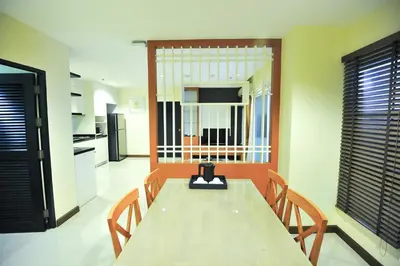 a dining room with a table and chairs and a kitchen at 42Grand Residence in Bangkok