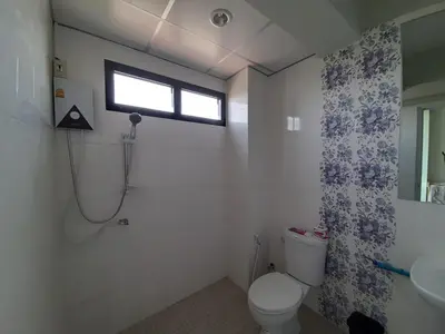 a bathroom with a toilet and a sink and a window at Vanlisut Hotel Ngamwongwan in Nonthaburi