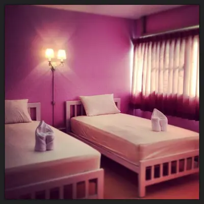 two beds in a room with purple walls at Baan Khun Rak in Bangkok