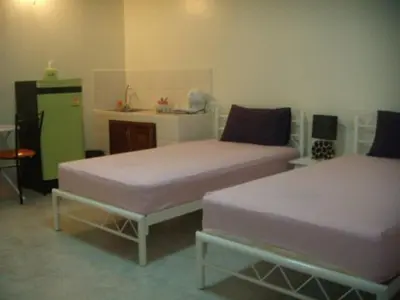 a room with two beds and a green refrigerator at Baan Khun Rak in Bangkok