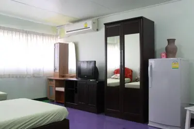 a bedroom with a refrigerator and a tv in it at Baan Khun Rak in Bangkok