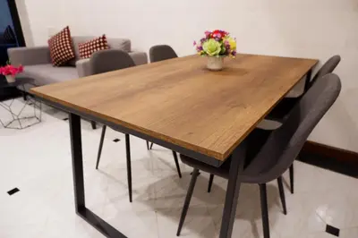 a wooden table with chairs and a vase of flowers on it at Lisa'House in Bangkok