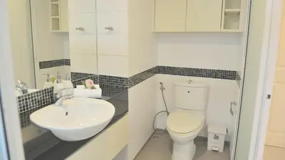 a white bathroom with a sink and a toilet at Duplex 21 Apartment in Bangkok