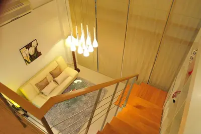 a living room with a chair and a staircase at Duplex 21 Apartment in Bangkok