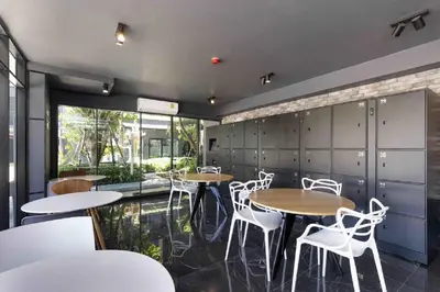 a restaurant with tables and white chairs and windows at The Excel Groove Condo at Lasalle 52 in Bangkok