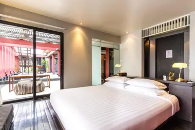 a bedroom with a large white bed and a window at Loogchoob Homestay in Bangkok