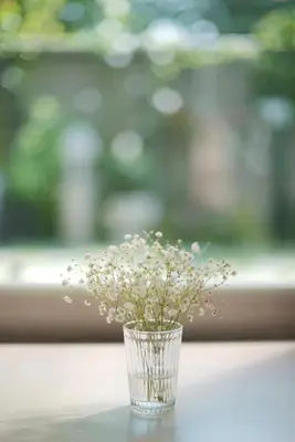 a glass vase filled with white flowers on a table at The Qube fifty Hotel in Bangkok