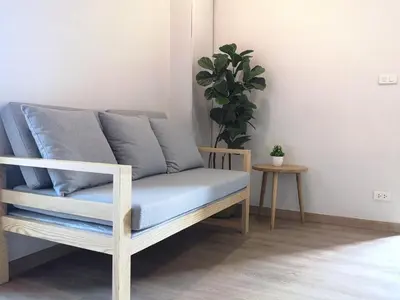 a couch in a living room with a plant at YAKTHAI POSHTEL in Bangkok