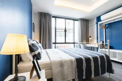 a bedroom with a bed and a lamp and a window at Cozy Studio 1 in Sathorn, BTS Saint Louis in Bangkok