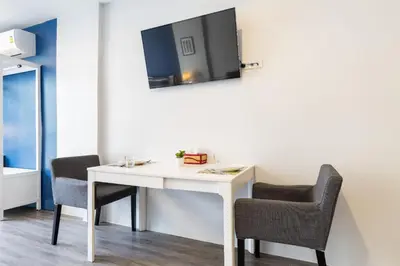 a white desk with two chairs and a tv on a wall at Cozy Studio 1 in Sathorn, BTS Saint Louis in Bangkok