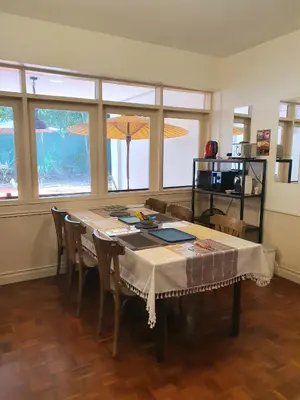a dining room with a table and chairs and windows at Villa Thaï Sukhumvit Asok Nana in Bangkok