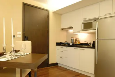 a kitchen with a wooden table and a refrigerator at The Narathiwas Hotel & Residence Sathorn Bangkok in Bangkok