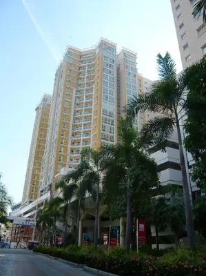 a tall building with palm trees in front of a street at The Narathiwas Hotel & Residence Sathorn Bangkok in Bangkok