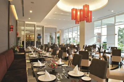a restaurant with tables and chairs in a room with windows at The Narathiwas Hotel & Residence Sathorn Bangkok in Bangkok