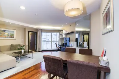 a dining room and living room with a table and a couch at The Narathiwas Hotel & Residence Sathorn Bangkok in Bangkok