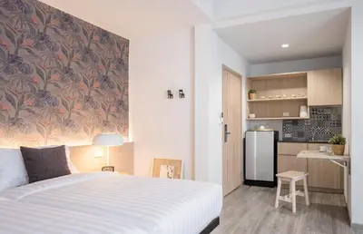 a bedroom with a white bed and a kitchen at China Cozy Asoke in Bangkok